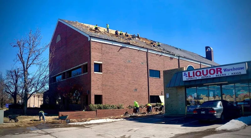 Crew removing the roof from a large brick office and retail building