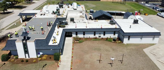 Aerial view of a crew installing a new flat roof on a church