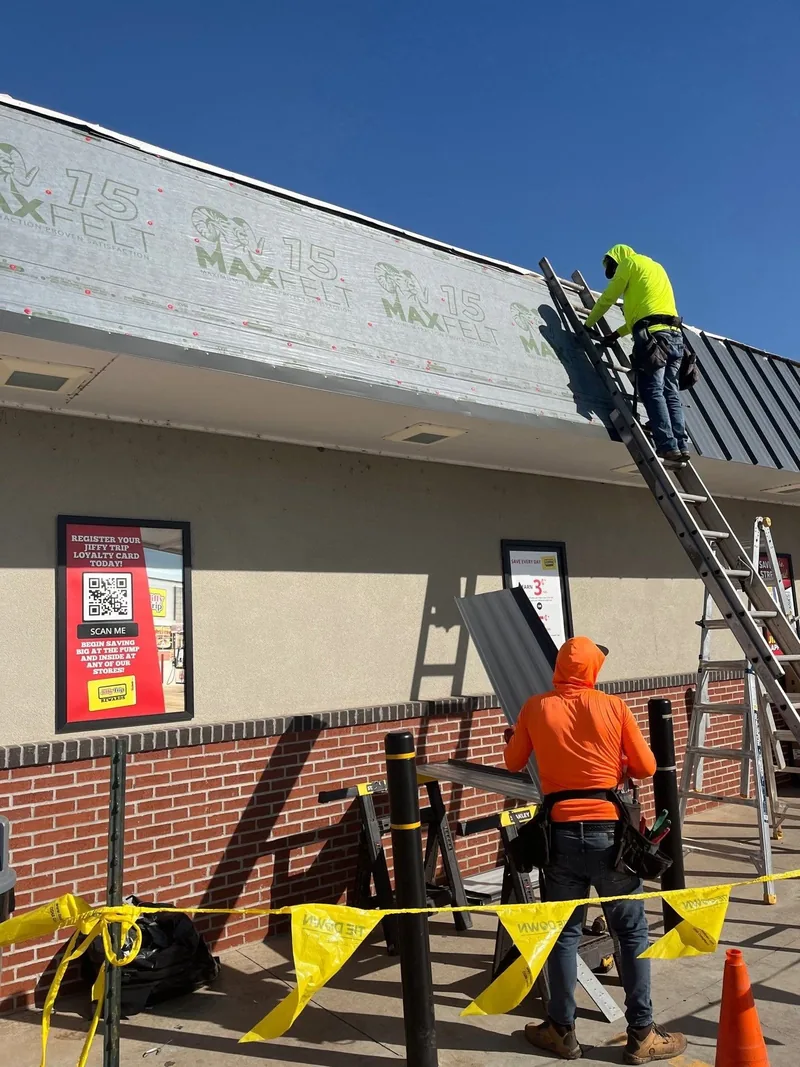 Roofing crew installing metal panels on a commercial building