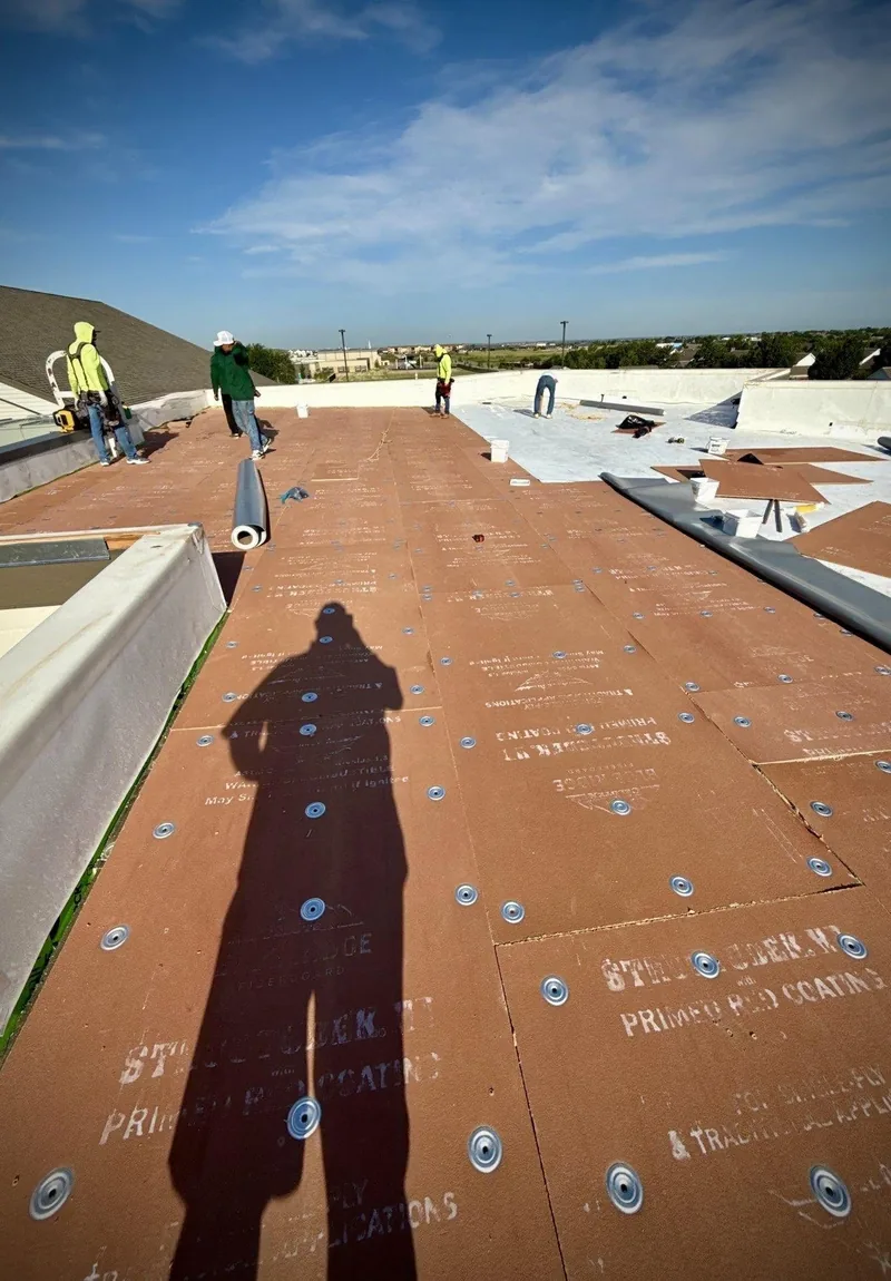 Roofing crew installing coverboard on a commercial roof