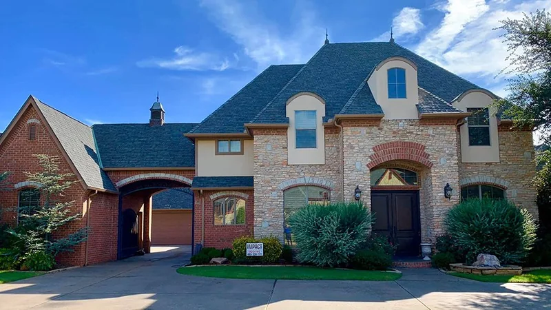 Two-story brick home with a completed dark shingle roof