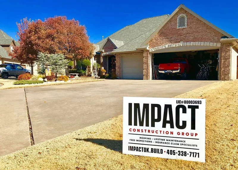 Residential roof replacement behind an Impact Roofing yard sign