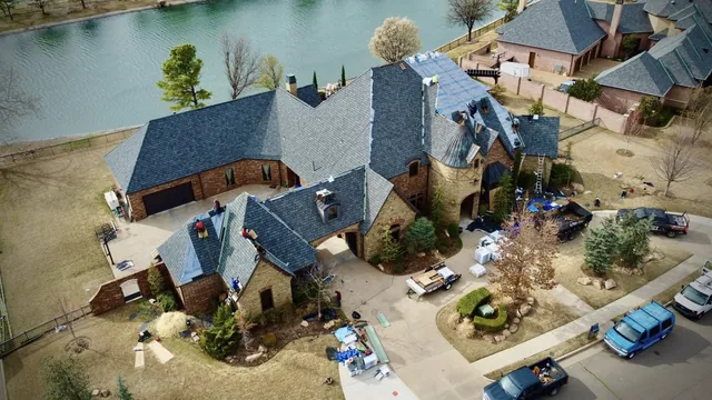 Aerial view of a roofing crew working on a large lakefront home