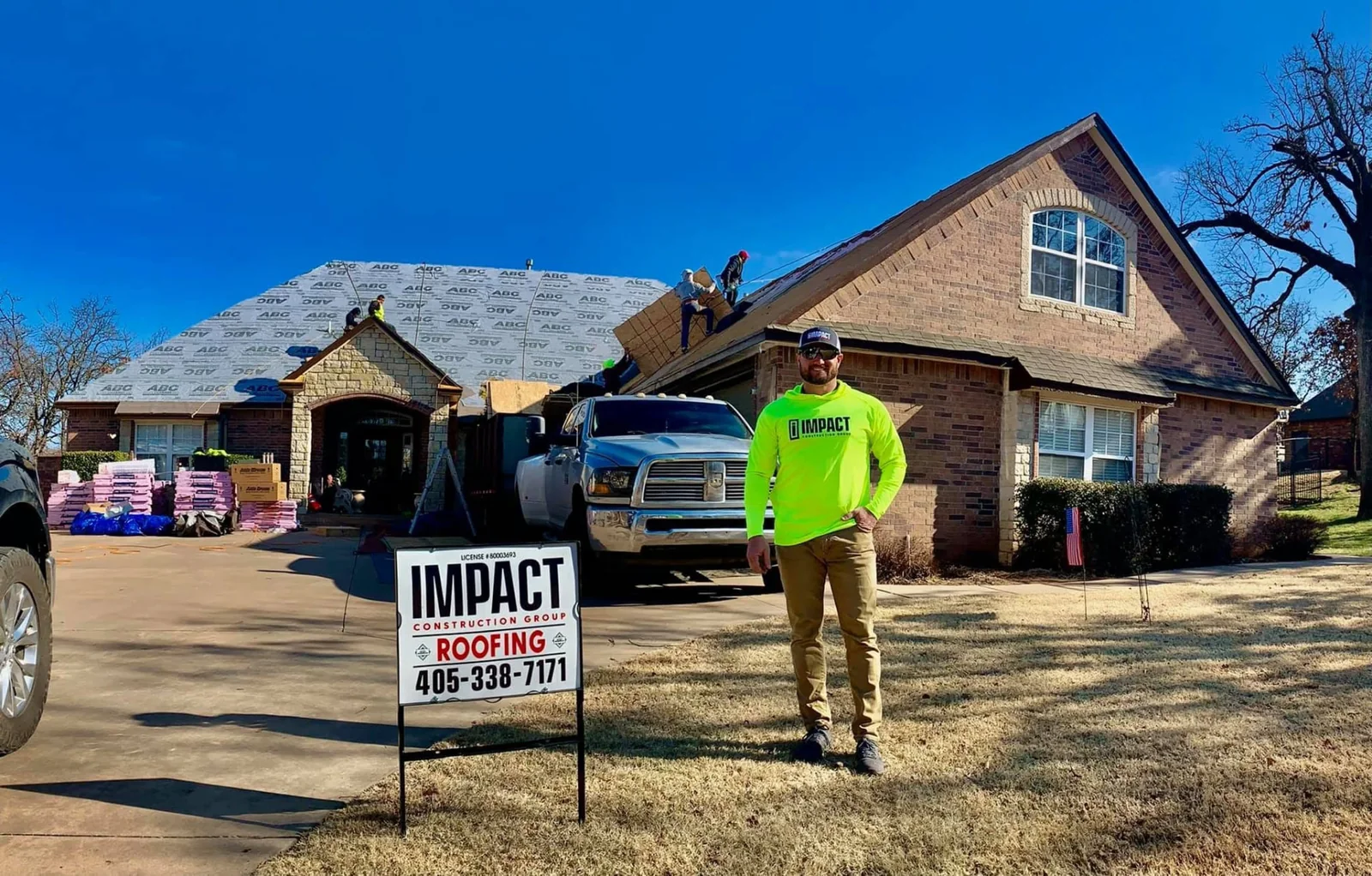 Roof replacement in progress behind an Impact Roofing yard sign