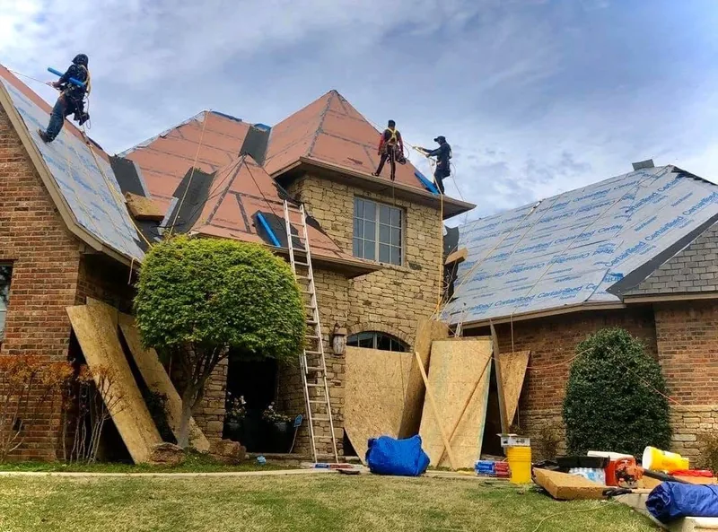 Roofing crew removing shingles from a steep residential roof